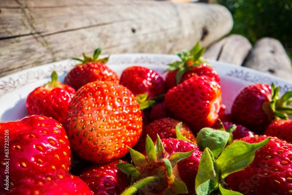 Fototapeta Close-up strawberry crop lying in a plate on rural wooden steps. The concept of healthy food, vitamins, agriculture, market, strawberry sale