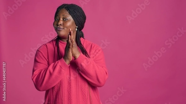 Fototapeta Glamorous female with african american ethnicity motioning to the side with left-hand. Stunning black woman with elegant style gesturing and applauding in front of pink color background.