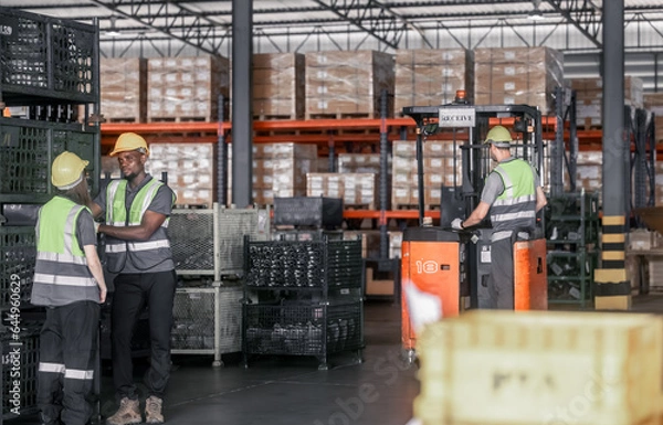 Fototapeta Warehouse forklift operator moves, stores merchandise, stays in touch with team, boss via radio