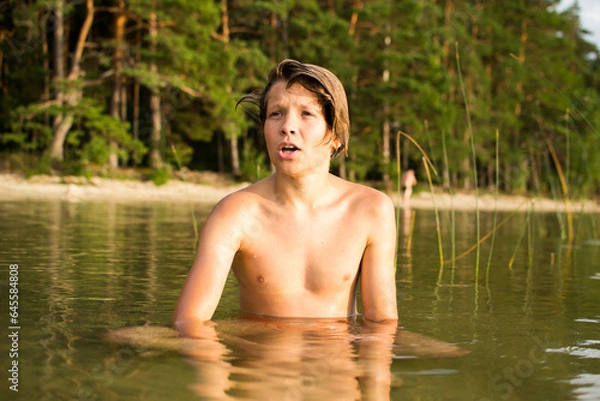 Fototapeta Camping weekend, teenage boy, lake and sandy shore.