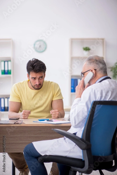 Fototapeta Young male patient visiting old male doctor