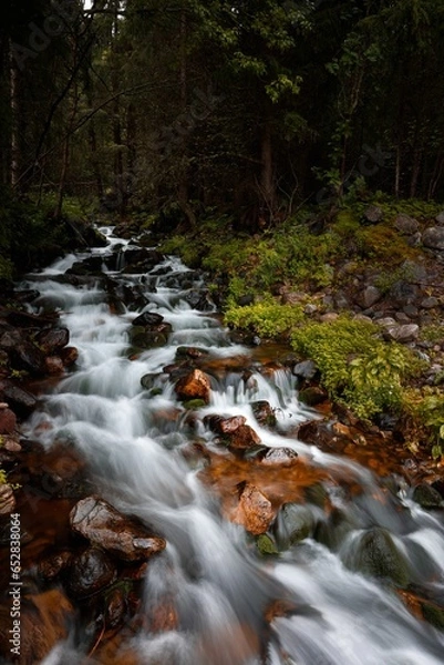 Fototapeta Long exposure of a stream of water winding its way through a rocky landscape