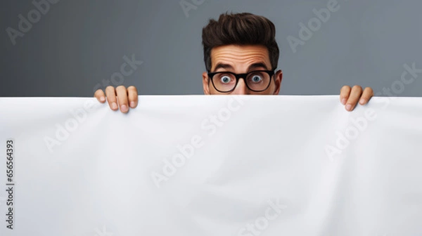 Fototapeta Man with glasses hiding away out of fear and scared behind banner blanket with copy space.