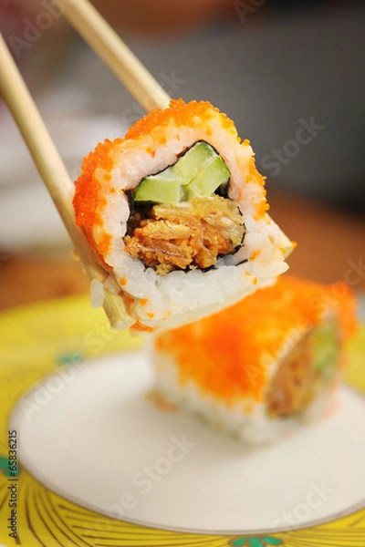 Fototapeta Sushi holding with bamboo chopsticks