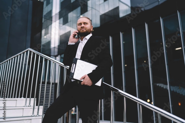 Fototapeta Successful pensive businessman making phone call