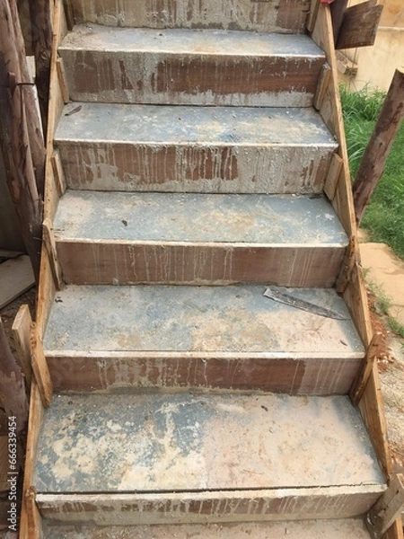 Fototapeta Cement staircase with construction hardware being constructed using wooden forms to fill the concrete.