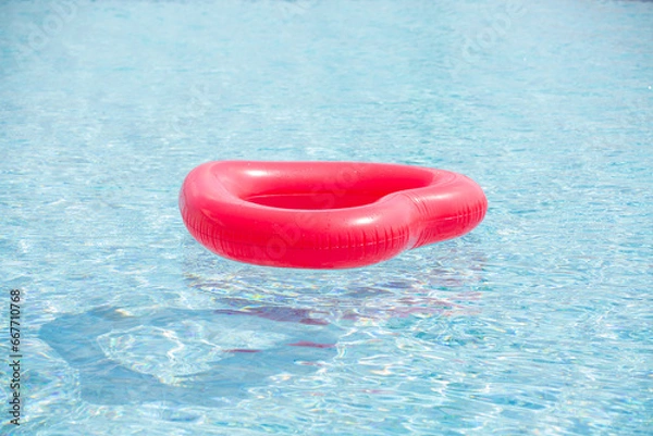 Obraz Red inflatable ring floating in the swimming blue pool water on summer day