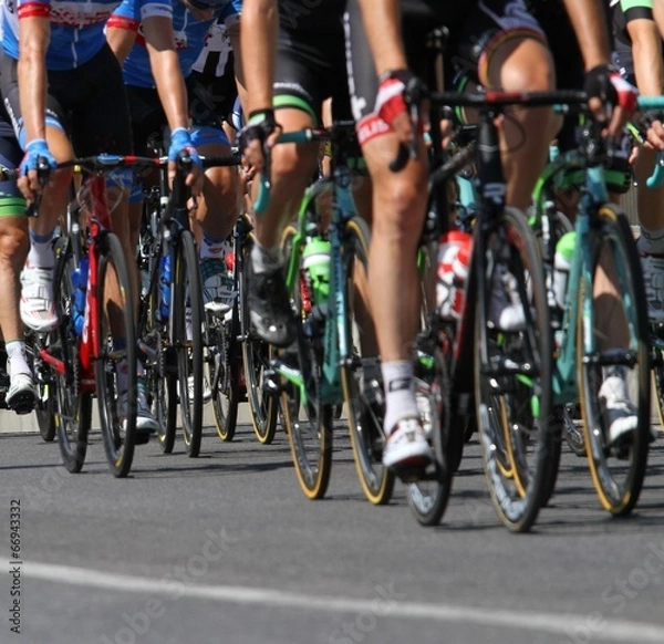 Fototapeta Group of cyclists ride uphill vigorously during the cycling race