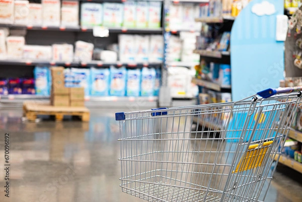 Fototapeta Abstract blurry photo of a supermarket with an empty shopping cart concept.