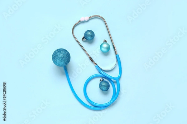 Fototapeta Christmas composition with stethoscope and baubles on blue background