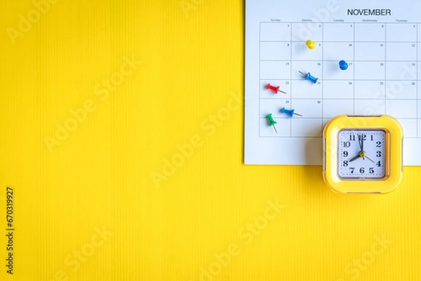 Fototapeta Calendar with colorful pins and clock, top view. On yellow background, copy space.