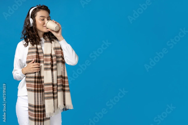 Fototapeta Girl in winter clothes with coffee, on a blue background.