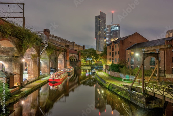 Fototapeta Castlefield in Manchester, UK, at night, with a modern skyscraper in the back