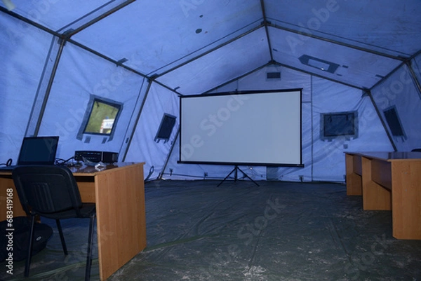 Fototapeta Interior of the mobile headquarter of State Rescue Service deployed for an accident case, training. Laptops, tables, large screen under the tent.