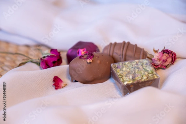 Fototapeta Chocolate pieces with flowers and roses on pink and white background also with mock up space