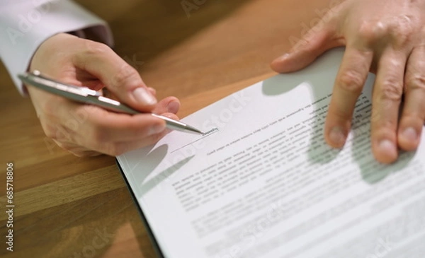 Fototapeta Hands of businessman with pen signing contract document at table closeup. Official certification of important papers concept