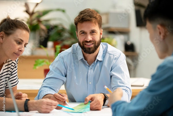 Fototapeta Adult businessman looking at the camera while sitting at table