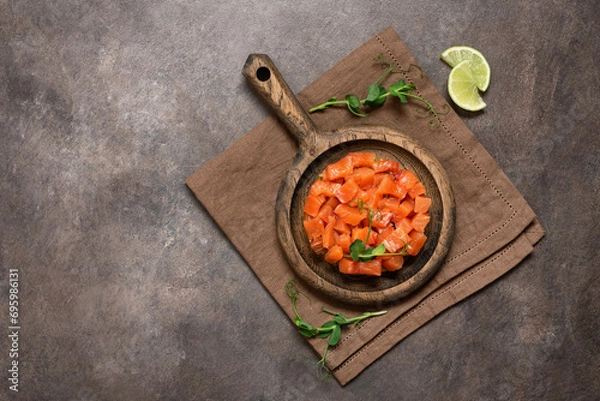 Fototapeta Raw salmon tartare with avocado served in culinary ring on dark rustic background. Top view, flat lay, copy space