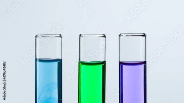 Fototapeta Concept of science and biotechnology. Laboratory glassware on white background. Test tubes filled with blue, green and purple liquid. Close up.