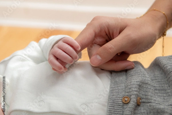 Fototapeta Les doigts du bébé qui tiennent la main de ses parents