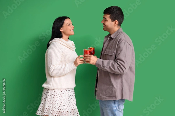 Fototapeta Young couple with glasses of mulled wine on green background