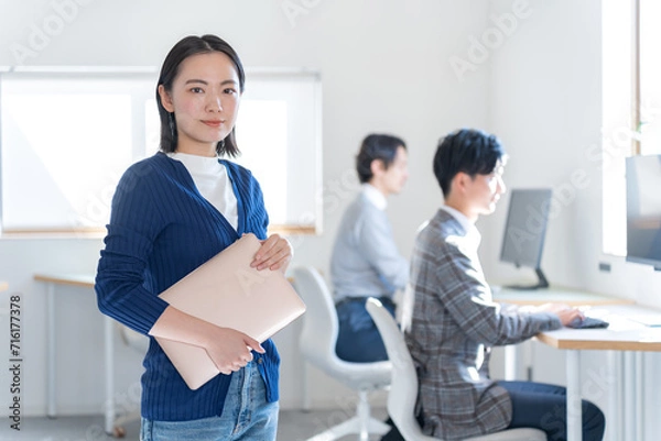 Fototapeta オフィスでパソコンを持つ私服の女性