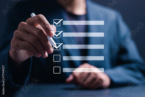 Fototapeta Checklist concept. Businessman use pen Checking mark on checkboxes for business performance monitoring and evaluation.