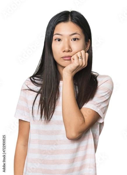 Fototapeta Young Chinese woman in studio setting biting fingernails, nervous and very anxious.