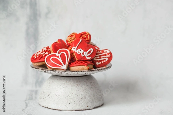 Fototapeta Homemade ginger cookies in the shape of a heart in red icing sugar. Delicious ginger cookies heart on a light concrete background. Freshly baked gingerbread cookies for Valentine's Day.