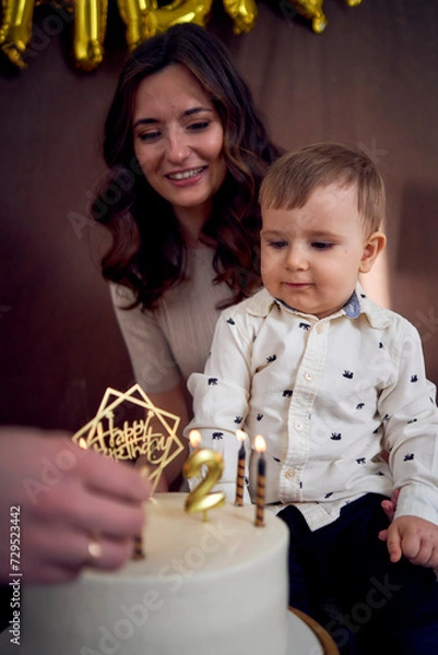 Fototapeta emotional parents watch as their son blows out the candles on the birthday cake