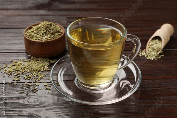 Fototapeta Aromatic fennel tea and seeds on wooden table, closeup