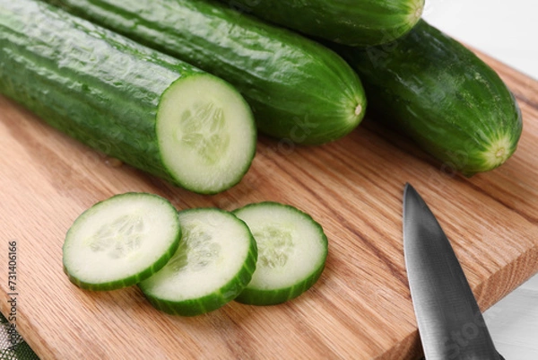 Obraz Fresh cucumbers and knife on wooden cutting board, closeup