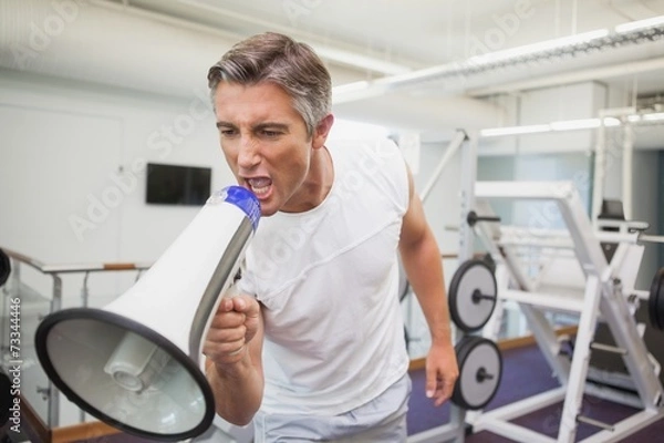 Fototapeta Angry personal trainer shouting through megaphone