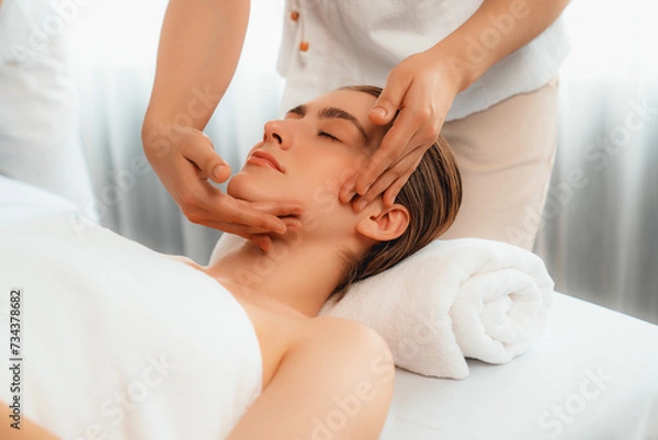 Fototapeta Caucasian woman enjoying relaxing anti-stress head massage and pampering facial beauty skin recreation leisure in dayspa modern light ambient at luxury resort or hotel spa salon. Quiescent