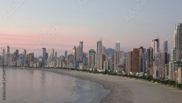 Fototapeta Sunrise on Balneário Camboriú beach, Santa Catarina, Brazil, with buildings in the blurred background.