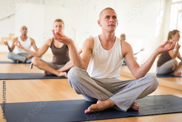 Fototapeta Portrait of man practicing yoga lesson at group class, maintaining healthy lifestyle