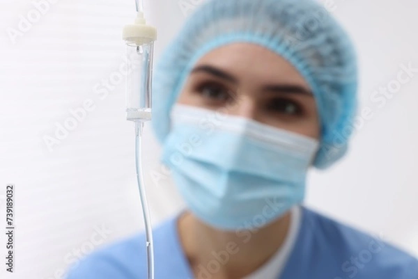 Fototapeta Setting up IV drip. Nurse on blurred background, selective focus