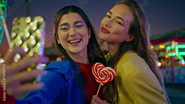 Fototapeta Joyful friends making selfie at night luna park closeup. Happy girls having fun