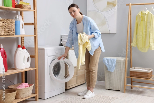 Fototapeta Beautiful woman with sweatshirt near washing machine in laundry room