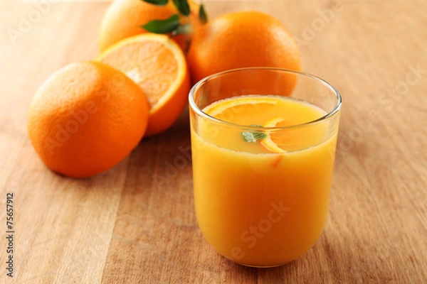 Fototapeta Glass of orange juice with slices on wooden table background