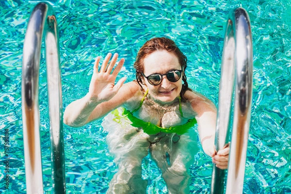 Fototapeta Active smiling mature Caucasian woman walks out of outdoor swimming pool satisfied with her workout. Healthy lifestyle and sport concept