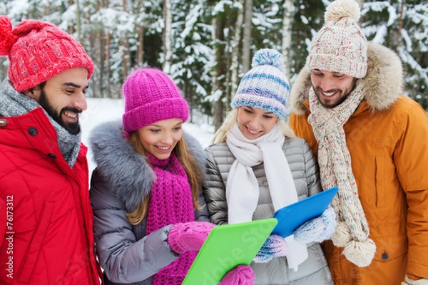 Obraz smiling friends with tablet pc in winter forest