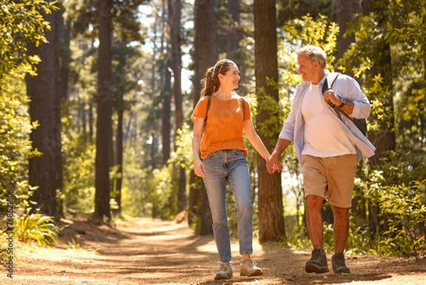 Fototapeta Senior Retired Couple Holding Hands Hiking Along Trail In Countryside