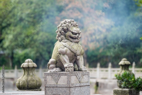 Fototapeta stone lion sculpture on the fence in the park