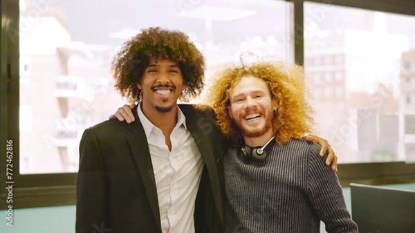 Fototapeta Coworkers with curly hair embracing in the office