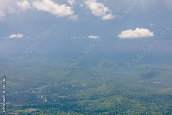 Fototapeta vue en hauteur d'un terrain sauvage avec des arbres verts et des nuages dans le ciel lors d'une journée d'été