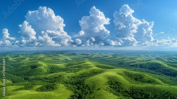 Fototapeta   An aerial view of a verdant valley beneath a clear blue sky, dotted with billowing white clouds above