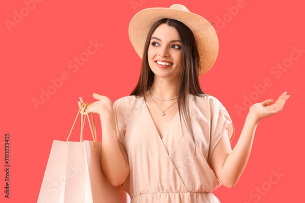 Fototapeta Young woman with shopping bags on red background