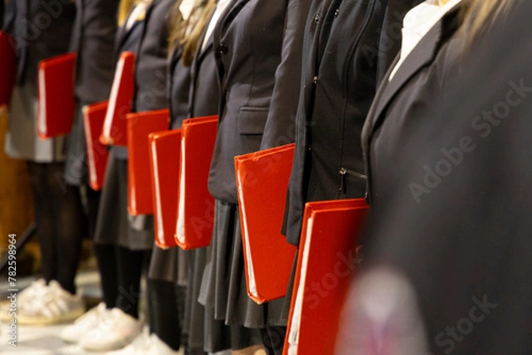 Fototapeta row of kids holding a red book closed under their arms