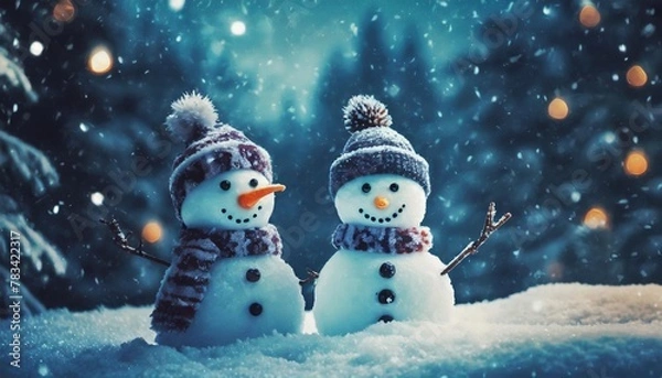 Fototapeta two little snowmen in caps on snow in the winter background with a funny snowman christmas card